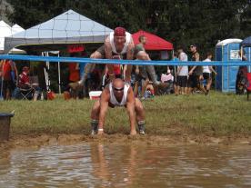 Mudd volleyball image of one player jumping over another looking at the camera